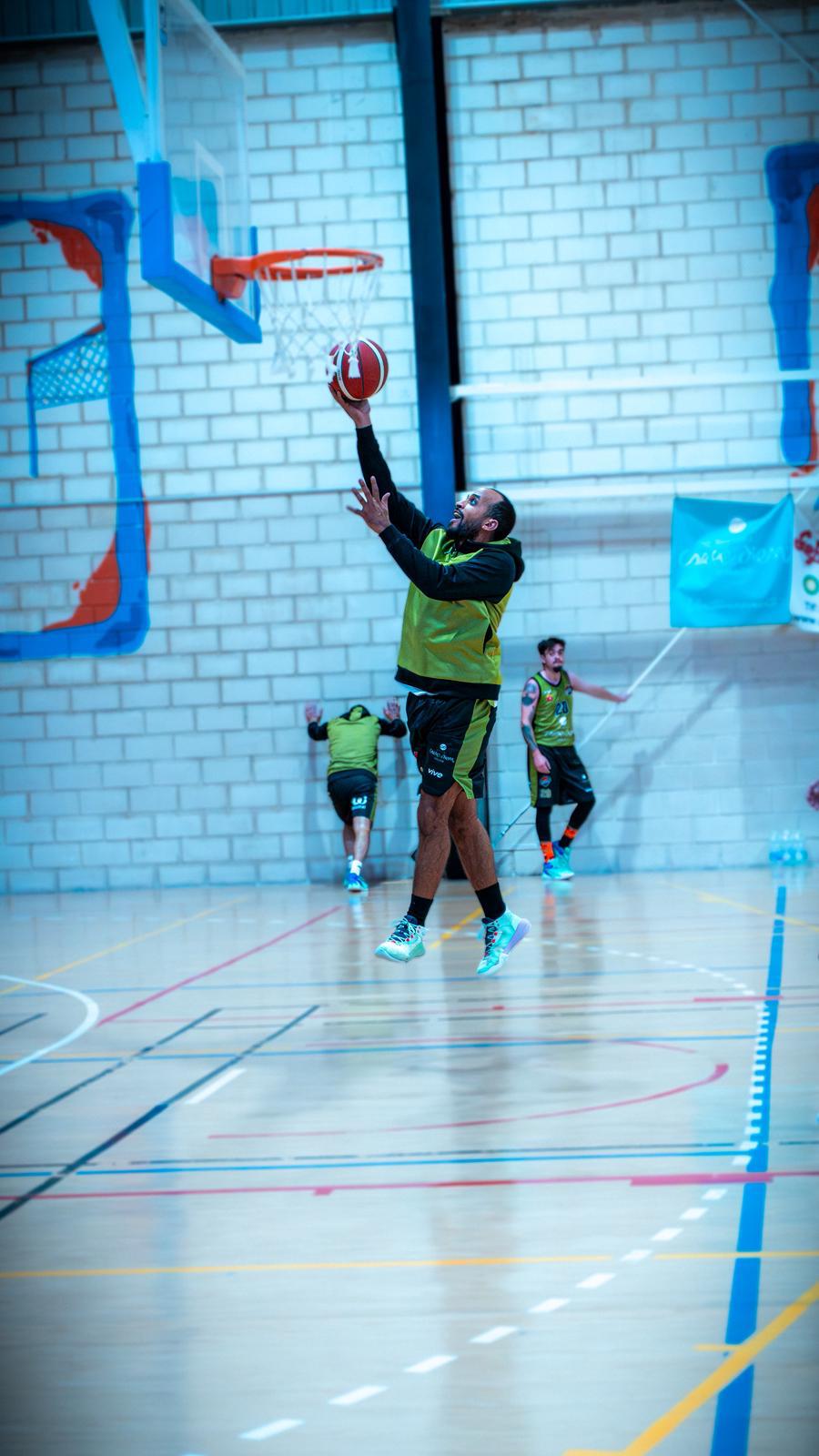 Jugador de baloncesto realizando una entrada a canasta en una cancha cubierta