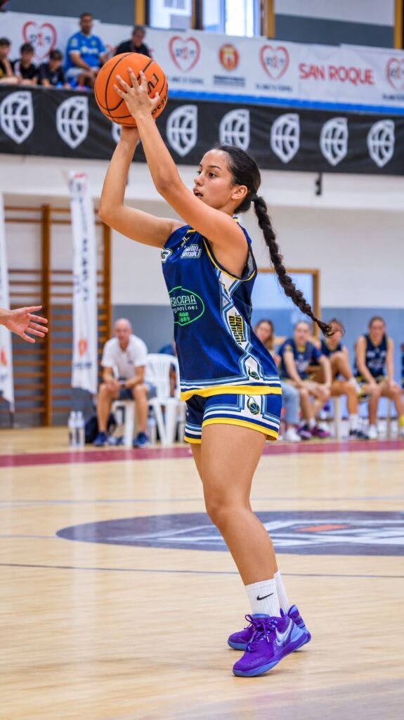 Jugadora de baloncesto preparando un lanzamiento en una cancha cubierta